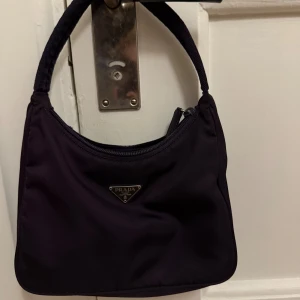 Prada väska  - Lila Prada väska köpt på vestiere collective, kan skicka kvitto vid intresse! Den är i fint skick 