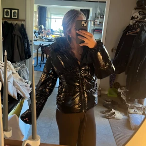 Svart glansig dunjacka från Nelly - Varm, gosig och mjuk med stor luva💓