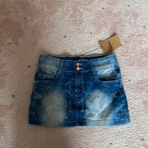 Blå jeanskjol med ✨glitter✨ och rosa detaljer💖 - Snygg kort jeanskjol i blått med coola slitningar och glitter i mönster på både fram- och bakfickor. Kjolen har två dekorativa knappar med rosa och beige detaljer samt en rosa patch med blå hjärtan bak. Perfekt för dig som gillar streetstyle ✨💖✨🫶🏻🫶🏻🫶🏻