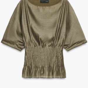 Olivgrön blus från Zara i satin - Olivgrön blus från Zara i glansigt satinliknande material. Modellen har korta vida ärmar, rund halsringning och smockad midja som ger en snygg siluett. Perfekt att styla med både jeans och kjol för en trendig look. Ny med prislapp💓nypris 559