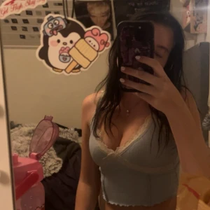 Ljusblå croppad omlottopp med spets - Säljer en ljusblå croppad omlottopp med ribbad struktur och v-ringning. Toppen har spetsdetaljer längs halsringningen och är ärmlös med smala axelband. Perfekt för dig som gillar en söt och trendig stil. Xxs men passar s och xs också 