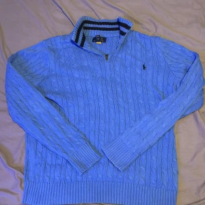 Ljusblå stickad polo Ralph lauren half zip - En oerhört snygg ljusblå polo Ralph lauren half zip. Den är stickad och i ett skönt och lyxigt material. Perfekt för alla tillfällen.