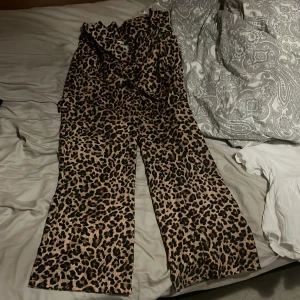 Leopardmönstrad kostymbyxor från Chiquelle XS - Säljer ett par snygga leopardmönstrade byxor från Chiquelle i storlek XS. Byxorna har vida ben och ett coolt heltryck i beige och svart. Perfekt för dig som vill sticka ut med ett djuriskt mönster och skön passform.