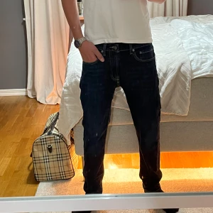 Dressman mörkblå jeans straight fit - Snygga dressman jeans i mörkblå tvätt med klassiska kontrastsömmar. Modellen har rak passform och normal midja, fem fickor och dragkedja. Perfekta för dig som gillar en clean och tidlös look. Passar till sneakers eller boots.