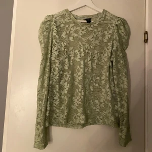 Ljusgrön spetsblus med puffärm - Säljer en ljusgrön blus från H&M med lång puffärm och rund hals. Blusen är helspets med blommigt mönster och har en luftig, loose passform. Perfekt för dig som gillar romantiska detaljer och vill sticka ut med en unik färg.
