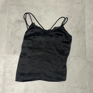 Linne med spets från ginatricot - Säljer ett svart Linne från ginatricot med spets och fin passform. Den har dubbla axelband och är normal i storleken.