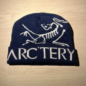 Mörkblå Arcteryx mössa  - Säljer en mörkblå Arcteryx mössa med vit text. Aldrig använd utan prislapp. Bara att höra av sig vid intresse och pris kan diskuteras vid snabb affär! One size storlek