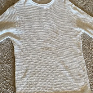 Vit stickad långärmad tröja - Säljer en vit långärmad tröja med snyggt stickat strukturmönster. Tröjan har rund hals och är gjord i ett mjukt material som känns skönt mot huden. Perfekt för dig som gillar stilrena och enkla plagg med lite extra textur.