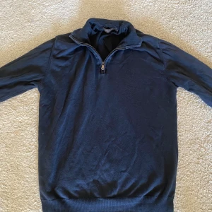 Marinblå half zip tröja - Snygg marinblå tröja med half zip och hög krage. Perfekt för dig som gillar en enkel och stilren look. Tröjan har långa ärmar och ribbad nederkant. Passar till både jeans och chinos för en chill vibe.