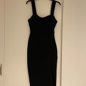 Svart klänning  - Säljer en svart långklänning från new yorker med breda axelband och figurnära passform. Klänningen har en snygg slits framtill och dragkedja i sidan för enkel påklädning. Perfekt för dig som gillar stilrena och eleganta plagg. Köpt från newyorker, men använd två gånger tidigare.
