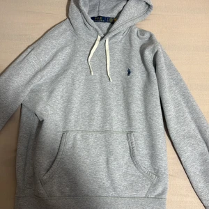 Grå hoodie från Polo Ralph Lauren - Snygg grå hoodie från Polo Ralph Lauren med klassisk broderad logga på bröstet. Tröjan är helt ny köpt en vecka sen 