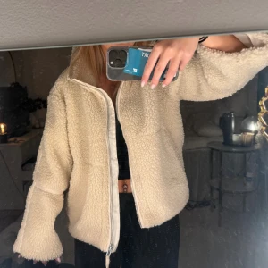 Beige teddyjacka med dragkedja - Supermjuk och fluffig teddyjacka i beige med hög krage och hel dragkedja framtill. Den är köpt i Polen så vet inte vad märket heter! Bra skick!