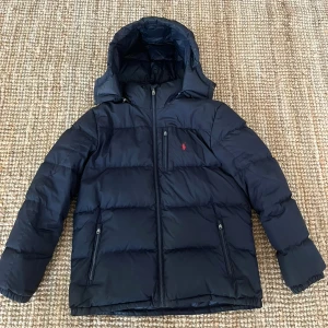 Polo Ralph Lauren Vinterjacka - ✅Äkta Blå Polo Ralph Lauren jacka. Skick: 8/10. Köpte den för cirka 2 år sedan för cirka 5000kr. Perfekt för dig som är cirka 178-168cm lång. Har blivit sydd vid ett mycket litet ställe på den högra ärmen, men det är inget som syns framifrån vid användning. Pris kan diskuteras, Skriv vid frågor🤝