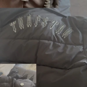 Svart pufferjacka från Trapstar - Säljer en svart pufferjacka från Trapstar med broderad logga på ryggen. Jackan har hög krage, dragkedja framtill och tryckknappar. Perfekt för kalla dagar och riktigt street i stilen.