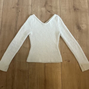 Vit frotté topp - Säljer en vit frotté topp från H&M med v-ringning och lång ärm.  Använd endast 2 ggr!❣️