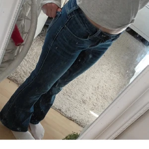 Blå bootcut jeans från Hollister - Snygga blå jeans från Hollister med klassisk bootcut-modell och låg midja. Jeansen har fem fickor, bälteshällor och stängs med dragkedja och knapp. Perfekt tvättad denim med lätt slitning för en cool look.