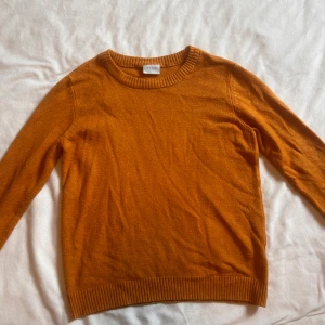 Orange stickad tröja från VILA - Snygg orange stickad tröja från VILA med rund halsringning och ribbade muddar. Perfekt för lager-på-lager och ger en poppig färg till din outfit. Långärmad och mjuk, passar grymt till både jeans och kjol.