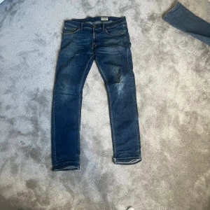 Tiger of Sweden mörkblå jeans W 33 L 32 - Snygga mörkblå jeans från Tiger of Sweden med klassisk femficksdesign och smal passform. Jeansen har subtila slitningar och kontrastsömmar, vilket ger en cool och modern look. Perfekta för dig som gillar stilrena och tidlösa jeans.