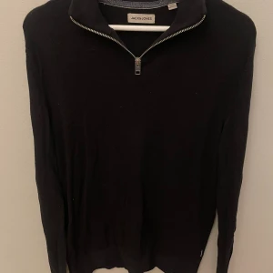 Svart half zip tröja Jack & Jones - Svart långärmad tröja från Jack & Jones med snygg half zip-dragkedja vid halsen. Enkel och stilren design som passar perfekt till jeans eller chinos. Mjuk och bekväm, perfekt för kyligare dagar.