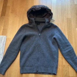 Grå stickad hoodie från Massimo Dutti - Säljer en grå stickad hoodie från Massimo Dutti med dragkedja och quiltad huva. Jackan är i storlek L, men sitter bättre som M.