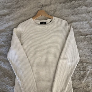 Vit randig tröja från Jack & Jones - Säljer en stilren vit långärmad tröja från Jack & Jones i storlek XS. Tröjan har tunna horisontella ränder och är tillverkad i mjuk bomull. Perfekt för dig som gillar en clean och enkel look med en twist.