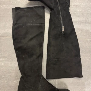 Svarta stövlar  - Säljer ett par svarta stövlar med platt sula och rund tå. Skorna är gjorda i mjukt material och har dragkedja på insidan för enkel påtagning. Perfekt för dig som vill ha en stilren och edgy look till höst och vinter.