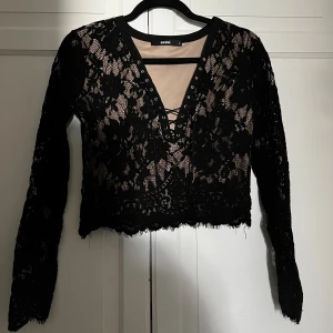 Svart spetsblus med snörning från Bik Bok - Säljer en svart blus från Bik Bok i storlek L. Blusen är croppad och har ett blommigt spetsmönster, långärmad design och v-ringad hals. Super snygg festligt spets tröja från Bikbok. Liten i storleken så inte riktigt L, mer som M. Tveka inte att skriva vid frågor!💕