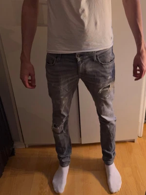 Grå skinny jeans med slitningar, strl 33/36 - Dessa säljs inte mer. Sjukt snygga och unika. När dom såldes gick dom för 1399kr. Säljer ett par grå jeans med skinny passform och slitna detaljer på benen. Modellen har klassiska fem fickor och låg midja. Materialet är jeans och färgen är en snygg mörkgrå ton med slitningar för en cool look.
