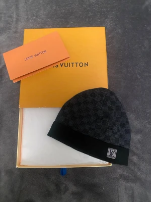 Louis Vuitton petite damier mössa  - Hej! Säljer en Louis Vuitton petite damier mössa i färgen svart Digtalt kvitto finns!!! Storlek one-size väldigt skööön nu till vintern, hör av er för mer info ///