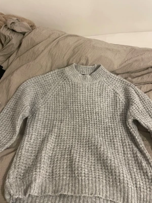 Grå stickad tröja från 157 - Säljer en grå stickad tröja från 157 i storlek M. Tröjan har en grovstickad struktur, rund hals med ribbad kant och långa ärmar. Perfekt för kyliga dagar och enkel att matcha med jeans eller mjukisbyxor.