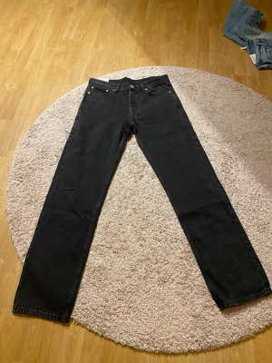 Svarta Weekday Klean jeans 31/34 - Svarta jeans från Weekday, modell Klean, med rak passform och midwaist. Tillverkade av ekologisk och återvunnen bomull. Helt nya, prislapp kvar och skickas i originalförpackning.