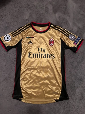 AC Milan Balotelli tröja - AC Milan fotbollströja med Balotelli 45 på ryggen,  i guld och svart med röda detaljer. Storlek M.