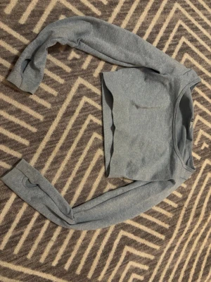 Grå croppad tränings tröja  - Säljer en stilren grå croppad tränings tröja med långa ärmar och rund hals. Toppen är enkel och har en slim passform, gjord på nylon och spandex.