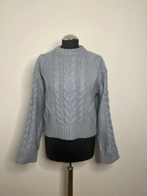 Ljusblå stickad tröja från H&M XS - Säljer en ljusblå stickad tröja från H&M i storlek XS. Tröjan har grova flätstickade detaljer både fram och på ärmarna, samt ribbad kant vid hals, ärmslut och nederkant. Perfekt för kyliga dagar och enkel att styla med jeans eller kjol.