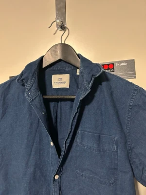 Blå kortärmad skjorta Scotch & Soda - Snygg blå skjorta från Scotch & Soda med korta ärmar och klassisk krage. Skjortan har knappar framtill och en bröstficka på vänster sida. Tillverkad i mjuk bomull som känns chill och passar perfekt till jeans eller shorts.