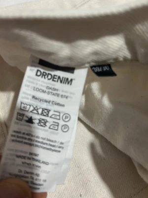 Vita jeans från Dr Denim - Säljer ett par vita jeans från Dr Denim, modell DASH. Byxorna är tillverkade av återvunnen bomull och har klassisk femficksdesign. Passar dig som gillar stilrena och ljusa jeans med enkel look. Märkespatch baktill i brunt med röd text.