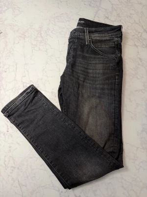 Mörkgrå jeans från Jack & Jones (slim/glenn) - Snygga mörkgrå jeans från Jack & Jones. Jeansen har en lätt tvättad look och är gjorda i mjukt bomullsmaterial med lite stretch för extra komfort. Storlek: W30 L32 