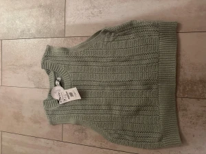 Stickad ärmlös tröja från Stradivarius - Snygg ljusgrön stickad tröja från Stradivarius i storlek M. Modellen är ärmlös med ribbade kanter vid hals och nederkant. Tröjan har ett diskret hålmönster och är gjord i 100% bomull, perfekt för lager-på-lager under vår och höst.