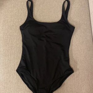 Svart baddräkt - En svart baddräkt med breda axelband. Lite rundad urringning fram och något djupare rygg. 