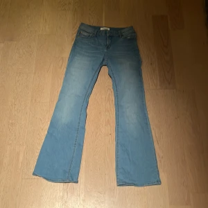 Ljusblå bootcut jeans från Lindex - Ljusblå jeans från Lindex i storlek 164 med bootcut-ben och klassisk femficksdesign. Jeansen har en slim passform upptill och är tillverkade i mjukt denimtyg. Perfekta för dig som gillar en retroinspirerad look med utsvängda ben.