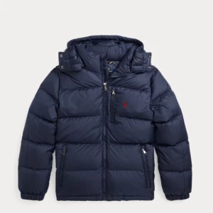 Mörkblå pufferjacka från Polo Ralph Lauren - Snygg mörkblå pufferjacka från Polo Ralph Lauren med huva och dragkedja framtill. Jackan har två sidofickor med dragkedja, elastiska muddar och ett rött Polo-logo broderat på bröstet. Jag har använt jackan under en vinter men säljer den för den är lite för stor den är så gott som ny. Priset kan diskuteras.