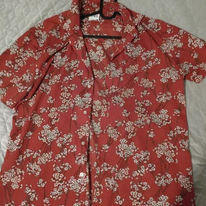 Zara, Röd blommig skjorta XL,44 - Detta är en röd Zara kortärmad skjorta för män med ett blommigt körsbärsblomsmönster. Perfekt för sommaren och stranden.   Storlek XL, 44 Den är helt ny inte använd den passade inte mig så säljer den nu. Den kostade 700kr i Zara.  