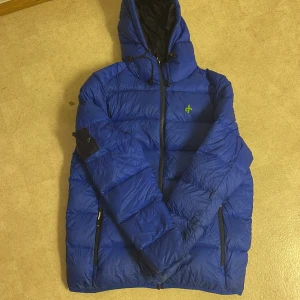 Blå dunjacka med huva - Blå dunjacka från Cross|sportswear med huva och dragkedja framtill. Jackan har defekter på armarna men är överlappad sen tidigare. Kanske kan någon annan fixa till det snyggare😇. I övrigt så håller värmen precis som vanligt👏🏼