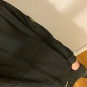 Svart ziptröja från Stone Island - Svart ziptröja från Stone Island med klassisk logotyp-patch på vänster ärm. Tröjan är stilren o är perfekt nu till vintern. Cond:9,5/10 ser helt oanvänd ut. Använd 3 gånger. 