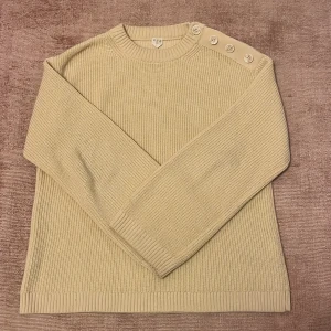 Gul stickad tröja - Snygg gul stickad tröja i storlek XS men passar mig som är m-L. Den har  fyra  knappar på ena axeln. Från arket!