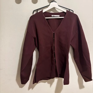 Vinröd kofta från Zara med v-ringning - Snygg vinröd kofta från Zara med v-ringad hals och knappar framtill. Modellen har långa ärmar och en stilren, enkel design som passar perfekt till jeans eller kjol. Materialet känns mjukt och bekvämt mot huden. Köpt för ett år sedan o knappt använd. 💞