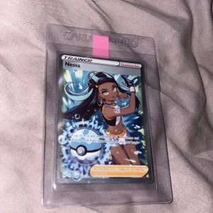 Nessa (Trainer Supporter) - Cool och färgstark Pokémon Trainer-kort med Nessa! Perfekt för samlare och spelare som vill boosta sin lek med en supporter från Pokémon-världen. Kortet är i skyddande plastficka och har snygg design som sticker ut i samlingen.