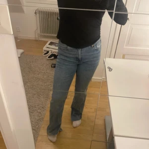 Blå bootcut jeans med slits - Säljer ett par blå jeans med bootcut-modell och snygga slitsar nertill på benen. Jeansen har normal midja och klassisk femficksdesign. Materialet är jeans i bomull och passformen är normal med lite utsvängda ben. Perfekta för dig som gillar en trendig och avslappnad look. Jag är ca 162