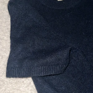 Mörkblå stickad tröja Gina Tricot - Mysig mörkblå stickad tröja från Gina Tricot med korta ärmar och rund halsringning. Tröjan har en loose passform och är tillverkad i ett mjukt material som passar perfekt för lager-på-lager under höst och vinter.