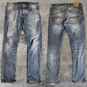 Blå jeans från Nudie Jeans - Säljer ett par sjukt feta blå jeans från Nudie Jeans med snygga slitningar. Jeansen har en galet fet tvätt och är väldigt unika då du inte kommer hitta någon med liknande! Modellen är den eftertraktade grim Tim modellen. Hör av er vid frågor!